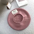 Close-up view of a pink knitted beret featuring a stylish alphabet patch on a rug - 55-60cm / Pink