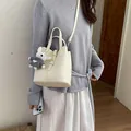 Sac seau minimaliste en cuir blanc crème avec porte-clé lapin montré sur un mannequin - Blanc (Avec Pendentif Coeur)