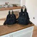 Mochilas negras minimalistas con cordón en dos tamaños sobre una mesa de madera. - L / Negro