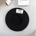 Detailed view of a soft black knitted beret hat featuring a vintage white cloth label - 55-60cm / Black