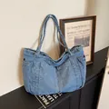 Detailed view of large blue denim tote bag with spacious side pockets and sturdy straps - Light Blue