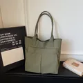 Large olive green casual tote bag for women displayed with minimalist lifestyle props - Green