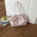 Een stijlvolle lichtroze draagtas met strikdetail en berenbedeltje op houten vloer. - Met Hanger / Roze