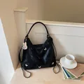 Multi-functional large black hobo bag with silver butterfly details in a cozy lifestyle setting - With Charm / Black