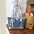 Blue denim tote bag with silver handles and a decorative white pearl lace bow charm - With Charm Style / Silver