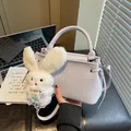 Close-up of a stylish lilac crossbody bag with a cute white plush bunny charm - With Charm / Light Purple