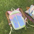 Detailed view of a colorful dopamine style outdoor hiking backpack on a green lawn. - Backpack / Large Capacity / Pink & Blue