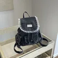Detail of vintage denim backpack featuring white lace ruffles and multiple pockets - Black