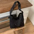 Black canvas tote bag with silver star pattern displayed in a cozy interior setting. - Black