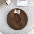 Detail view of brown knitted wool beret featuring a stylish letter patch decoration - 55-60cm / Brown