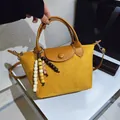 Sac à main élégant en daim jaune avec poignée en cuir et pompon décoratif en perles. - Jaune