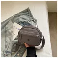 Close-up of grey casual nylon crossbody bag showing the fabric texture and brand logo tag. - Gray