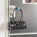 Stylish polka dot PVC baguette shoulder bag hanging on a modern blue door handle - Black