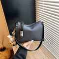 Detailed view of a trendy black textured pillow handbag with a cute white bear doll charm - With Charm / Black
