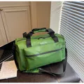 Detail view of a large green travel duffel bag featuring black handles and adjustable shoulder strap - Green