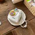 Macro detail of white mesh bucket bag with chunky rope strap and dinosaur charm keychain - With Charm / White
