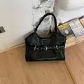Chic black tote bag with buckle detail shown in a cozy indoor lifestyle setting - Black