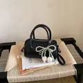 Sac polochon noir élégant avec un charme de nœud en perles sur une chaise tissée - Avec Pendentif / Noir