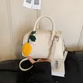 Elegant beige faux leather pillow bag featuring a stylish yellow lemon charm detail - With Charm / Off White