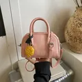 Elegant pink textured pillow bag featuring top handles and a stylish yellow woven charm - With Charm / Pink
