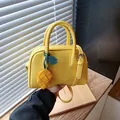 Stylish yellow pillow bag with a woven lemon charm and adjustable shoulder strap - With Charm / Yellow