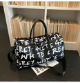 Macro view of stylish black leather duffel bag with white graffiti letters for travel - Black