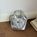 Macro view of a silver quilted metallic bucket bag featuring a chain strap and lock. - Silver (With Pendant)