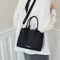 Detailed back view of a minimalist black leather bucket bag with unique knot handles and strap - Standard Type / Black
