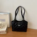 Elegante borsa tote in pelle trapuntata nera con fibbie argentate su scrivania in legno - Nero