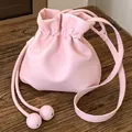Stylish candy-colored pink drawstring crossbody bag with textured leather finish. - Pink