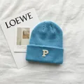 Close-up of a blue knitted beanie featuring a white embroidered letter P on white cloth - 55-59cm (Elastic) / Lake Blue