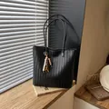 Κομψή μαύρη υφαντή τσάντα tote με ξύλινο μενταγιόν χαντρών σε ξύλινη επιφάνεια - Με Μενταγιόν / Μαύρο