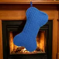 Chaussette de Noël bleue en tricot en forme d'os suspendue devant une cheminée chaude - Bleu