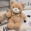 Schattige lichtbruine pluche teddybeer met geruite vlinderdas op een zachte warme deken. - Bruin