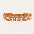 Macro detail of a bohemian tan leather disc belt featuring silver medallion accents - Bright Silver Camel