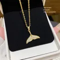 Detail shot of a sparkling mermaid tail pendant on a delicate gold chain necklace - Mermaid Tail (X335) / Gold