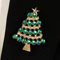 Detailed macro view of an elegant emerald green crystal Christmas tree brooch on black fabric - Dark Green Rhinestone Christmas Tree Style (10873) / Gold