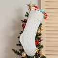 Classic white cable-knit Christmas stocking decoration hanging on a festive decorated tree - White Knitted Sock