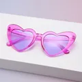 Nahaufnahme einer pinkfarbenen Herzsonnenbrille mit Glitzer und lila Gläsern im Display - Glitzerndes Violett