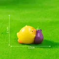 Cute miniature yellow chick figurine holding a purple eggplant for DIY landscape decor - Lying on Eggplant
