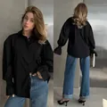 Front and back detail of a chic oversized black long-sleeved shirt with puff cuffs. - S / Tops / Black