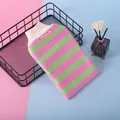 Close-up of rainbow striped exfoliating bath mitt on a black wire tray display. - Pink+Green