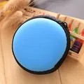 Close-up detail of a blue circular hardshell earphone storage pouch with a black zipper. - Blue