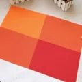 Stylish PVC heat resistant placemat featuring a warm orange and red grid pattern design - Orange
