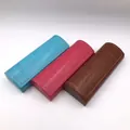 Detailed view of three PU leather glasses cases in blue, pink, and brown. - Faux Leather Foldover Glasses Case