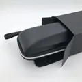 Detail view of the black portable eyeglass case partially inside its black cardboard box. - Medium Black Case