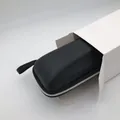 Detail of black portable sunglasses storage case coming out of a white paper box. - Medium White Case