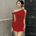 Detail view of a stylish red polka dot one-shoulder slim fit mini dress on model - S / Red