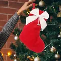 Detail of a red plush Christmas stocking with a white bow and a small silver bell. - Red