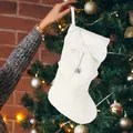 Elegant white Christmas stocking featuring a large bow and silver bell hanging on a tree - White